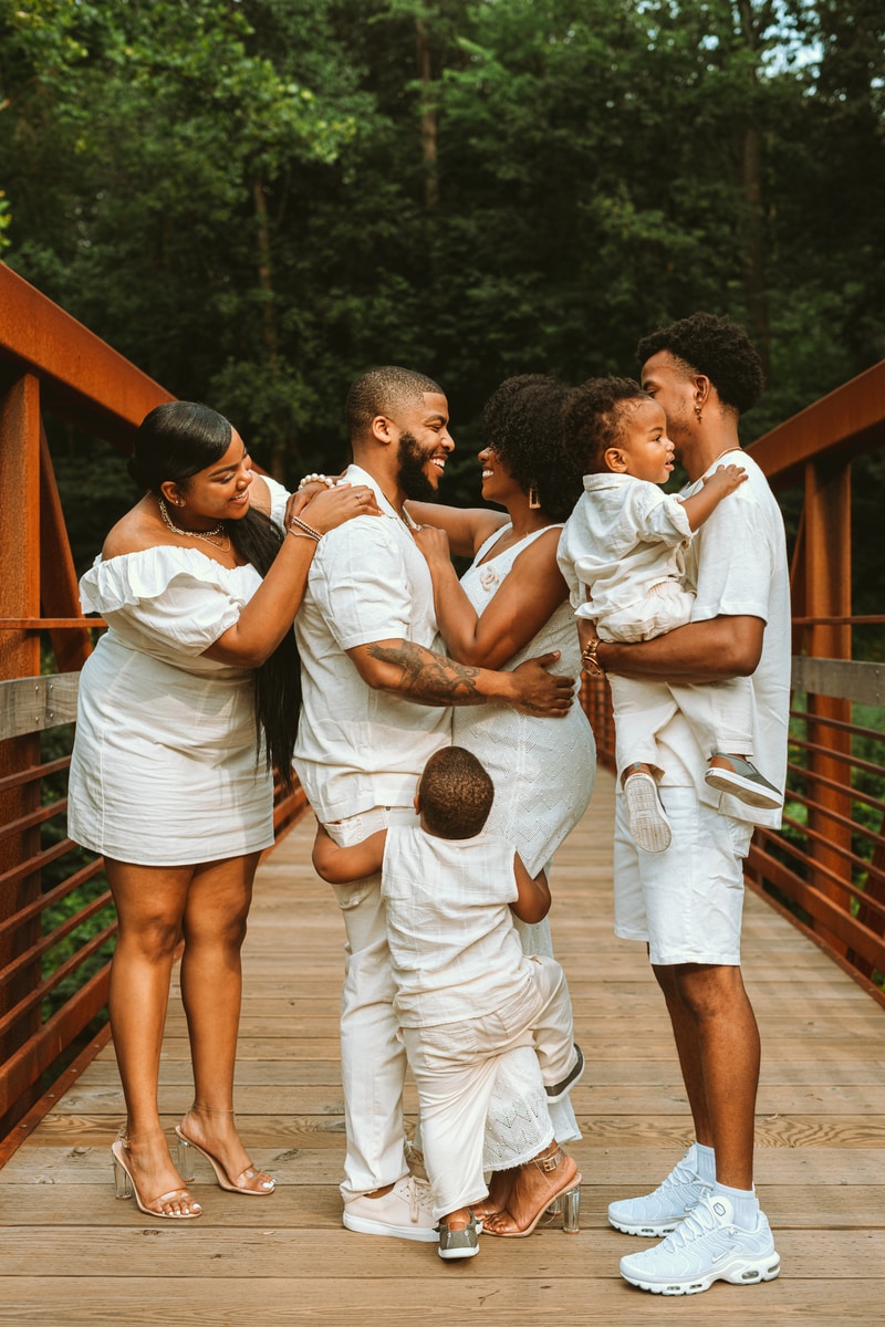 Mann im weißen Hemd trägt Baby im weißen Kleid