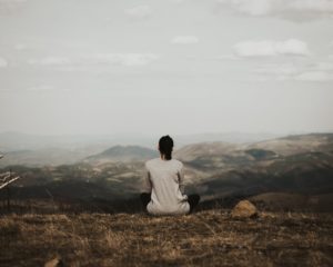 Frau sitzt auf einer Klippe mit Blick auf die Berge bei Tag