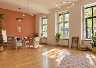 Heller böhmischer Gruppenraum mit Terrakotta-Wand, Pflanzen und großen Fenstern bei My International Therapy, Berlin