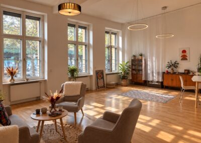 Sonnendurchfluteter Therapie- und Workshopraum mit grauen Sesseln und hohen Fenstern bei My International Therapy, Berlin